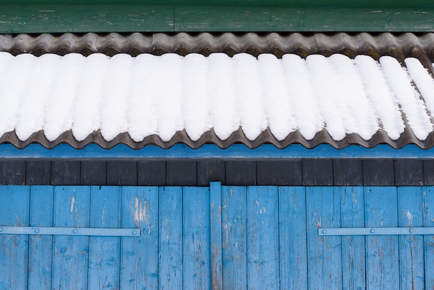 Winter background for design. abstract geometric fragment of old architecture. blue gates and slate roof in the snow