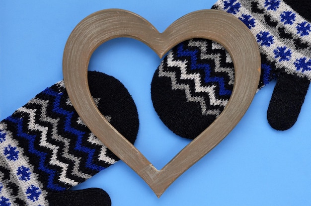 Winter background two mittens and a heart on a blue Valentine39s Day