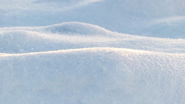 雪に覆われた波状の凹凸のある地面の表面の雪のテクスチャと冬の背景