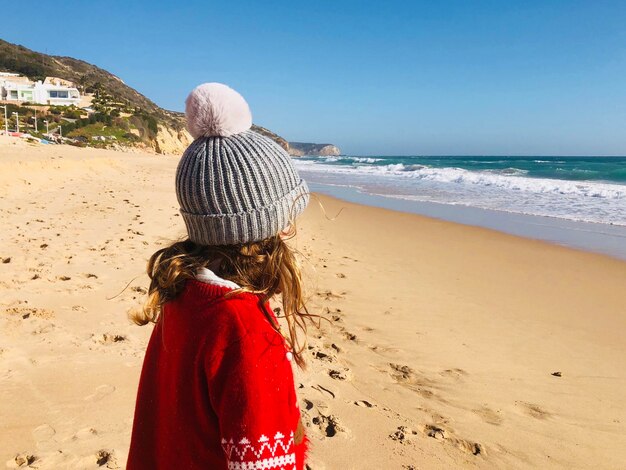 Photo winter at the beach with girl in bobble hat and christmas jumper