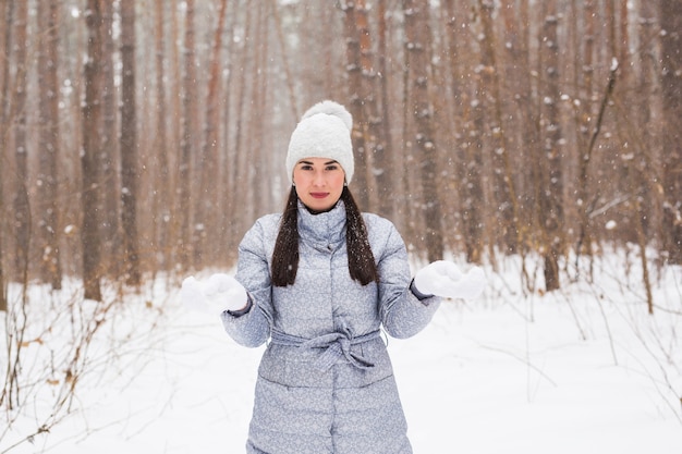 Winter, beauty and fashion concept - Portrait of young woman in coat at snowy nature wall