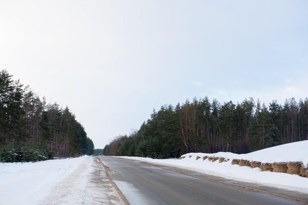 Winter besneeuwde dorpsweg en bos aan beide kanten