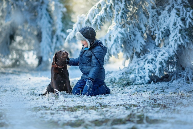 winter, boy playing with dog in winter forest