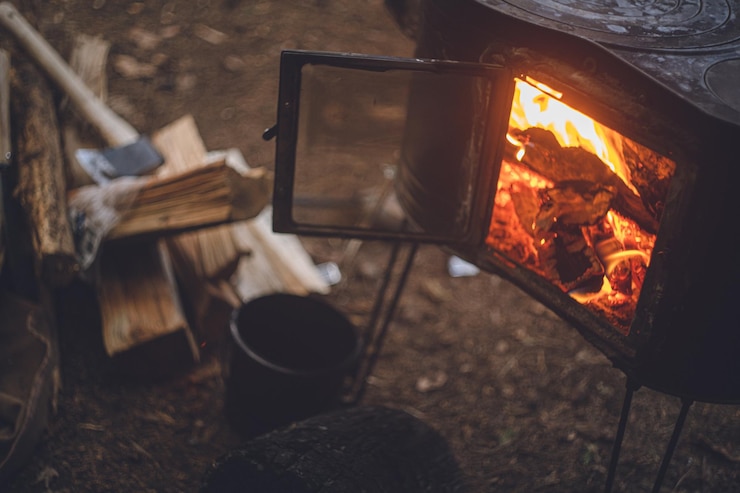 Photo winter camping chopping wood with an axe and stoking the wood stove