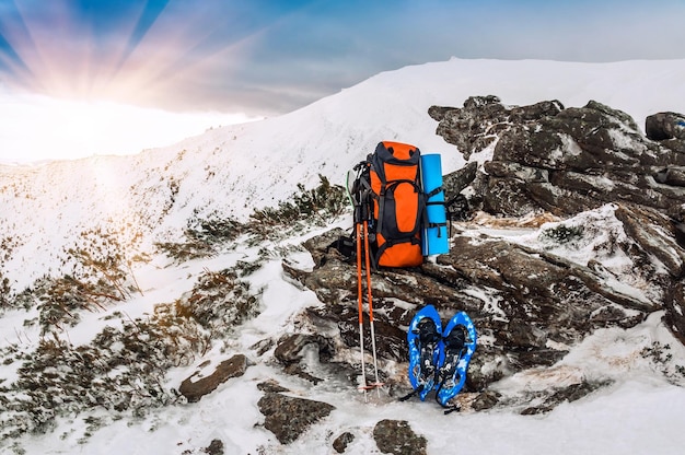 Winter camping equipment Backpack, Snowsoes and Hiking sticks in winter mountains