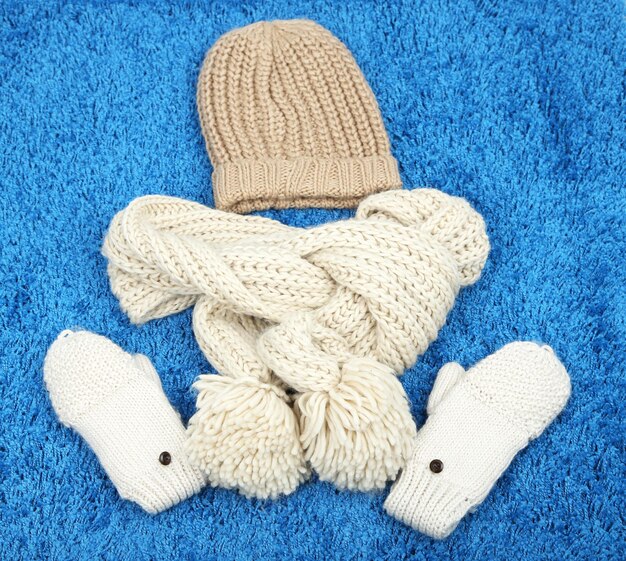 Winter cap, scarf and mittens, on color background