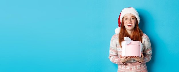 Winter and celebration concept happy redhead girl receiving christmas gift and thanking hugging box