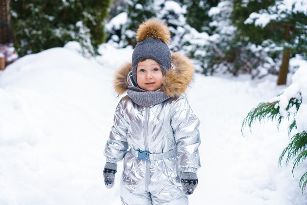 Зимой ребенок играет в снегу, зимняя сцена с ребенком, счастливое детство, рождество, счастье, мальчик в с ...