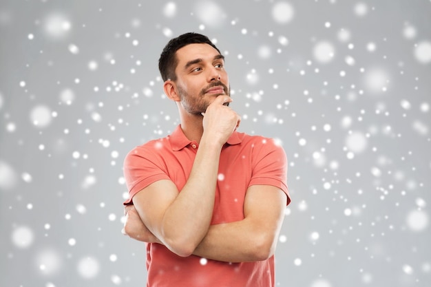 концепция зимы, рождества и людей - мужчина в футболке поло думает о снеге на сером фоне
