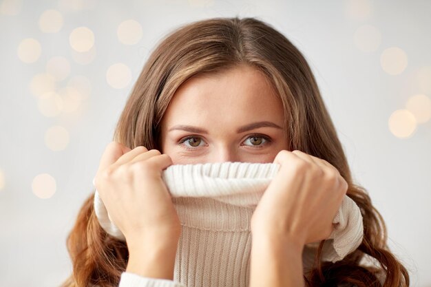концепция зимы, рождества и людей - молодая женщина или девочка-подросток, подтягивающая воротник пуловера