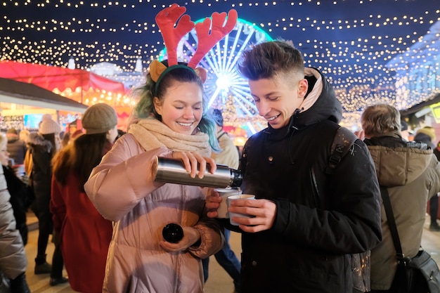 Winter Christmas portrait of happy teenagers boy and girl at holiday market