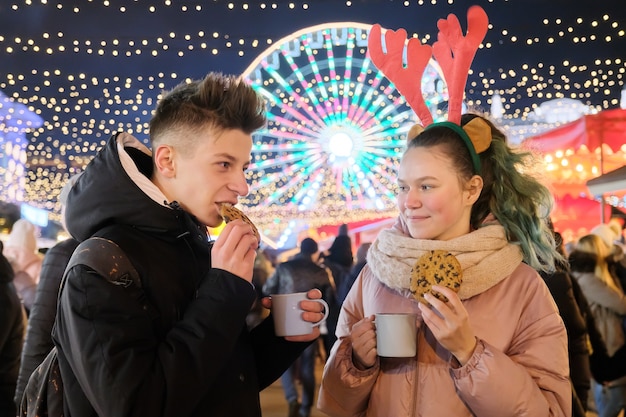 Winter Christmas portrait of a happy teenagers boy and girl at holiday market