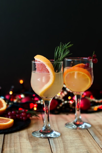 Winter cocktail with grapefruit, rosemary, orange and red currant in wine glasses.