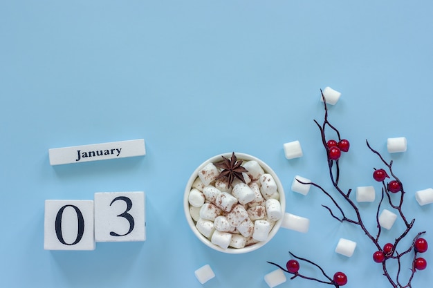 写真 冬の作文。白い木製のカレンダーキューブ。データ1月3日。ココア、マシュマロのカップ
