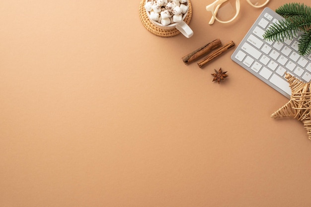 Winter concept top view photo of keyboard cup of cocoa with marshmallow wicker star glasses pine branch cinnamon sticks and anise on isolated beige background with copyspace