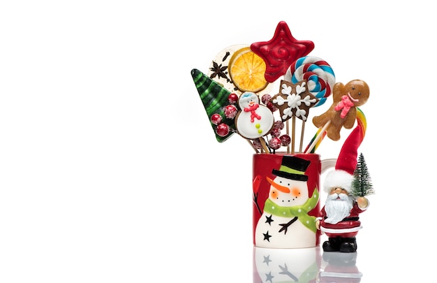 Winter concept with New Year decorations and sweets is isolated on a white background. Christmas festive card with Santa Claus, Christmas gingerbread and candy on sticks.