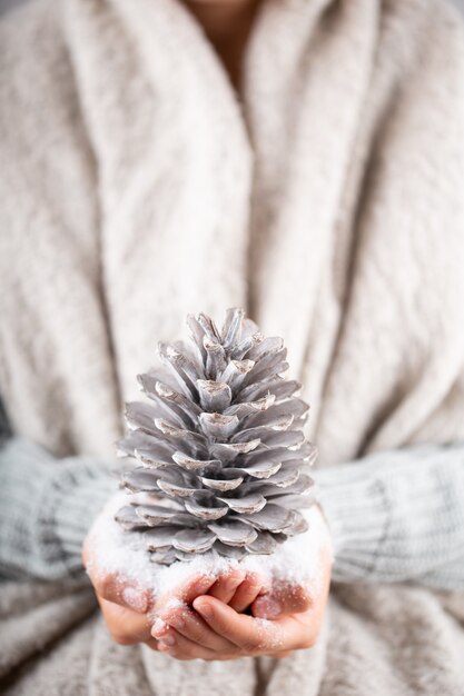 冬のコンセプト若い手がクリスマスの装飾を保持しています。クリスマスの装飾のアイデア。女性の手にクリスマスの装飾、金のボケ味の背景。