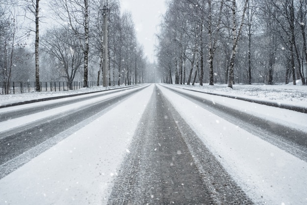 Foto strada campestre di inverno in nevicate. tracce delle ruote su una strada innevata