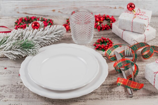 Winter couvert met kerst- en Nieuwjaars versieringen op witte houten tafel. Feestelijke tafelsetting voor het kerstdiner.