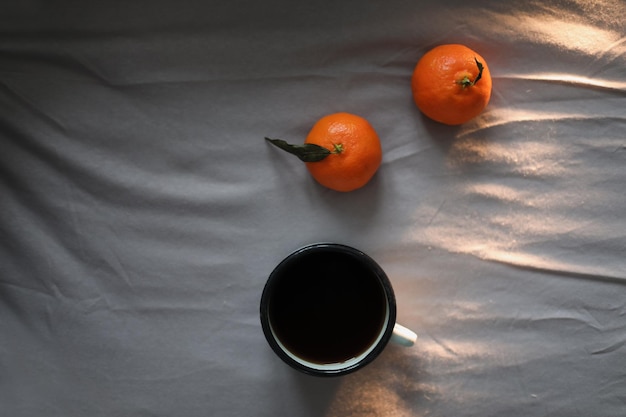 Winter cozy concept Cup with coffee and tangerines on the bed Copy space Flat lay top view