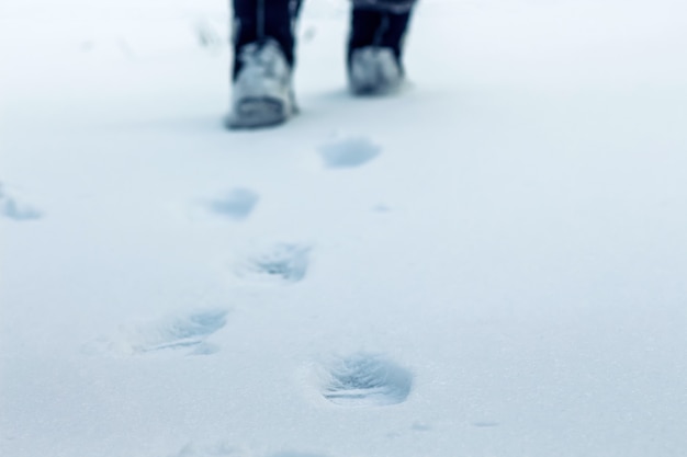 Photo on a winter day on the snow traces of human legs are visible, in the distance one can see feet, a symbol of purposefulness and movement forward