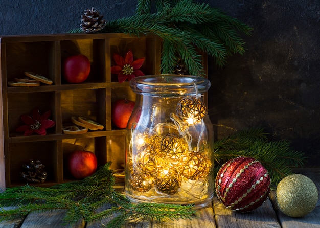 winter decor op een houten tafel: appels, dennentakken, kegels, ballen en garland