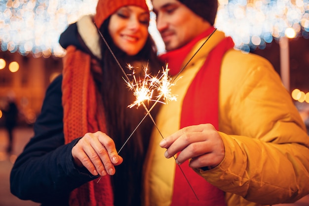 Sera d'inverno, amore coppia con stelle filanti all'aperto. uomo e donna che hanno incontro romantico sulla strada della città