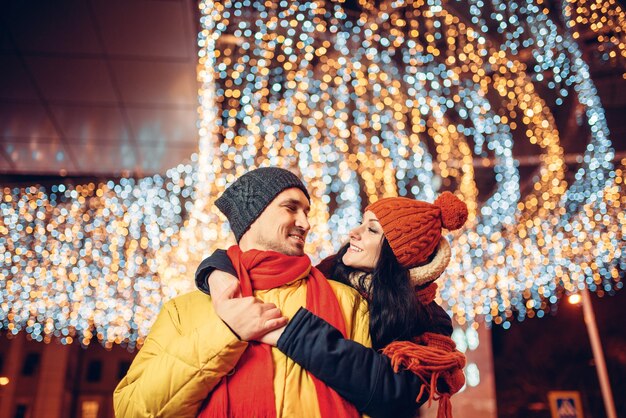 Foto sera d'inverno, abbracci sorridenti delle coppie di amore sulla strada. uomo e donna che hanno incontro romantico, relazione felice