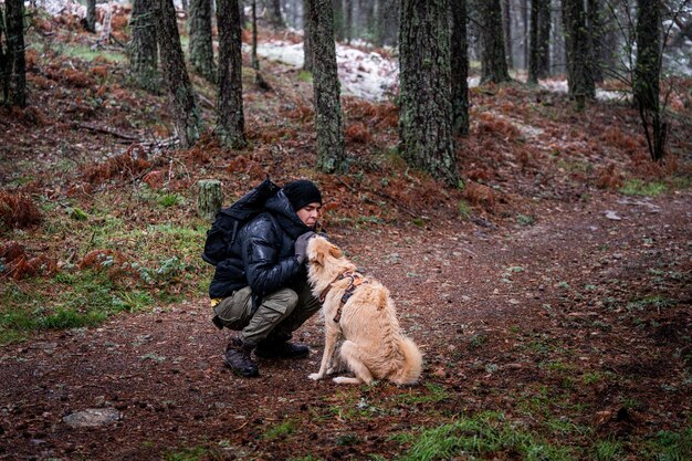 冬の探検家がスペインの雪に覆われた森でペット犬と優しい瞬間を共有する