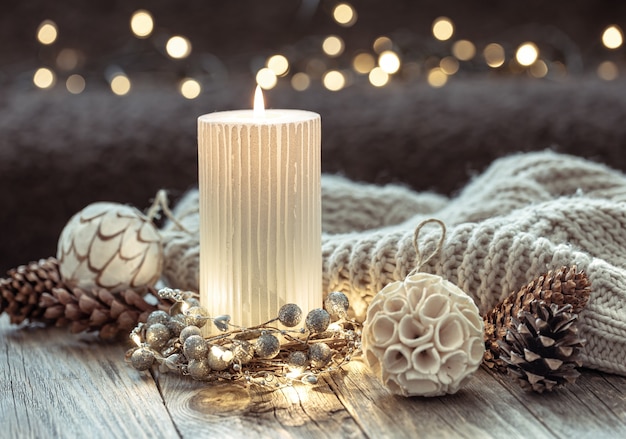 Winter festive background with burning candle and home decor details on blurred background with bokeh.