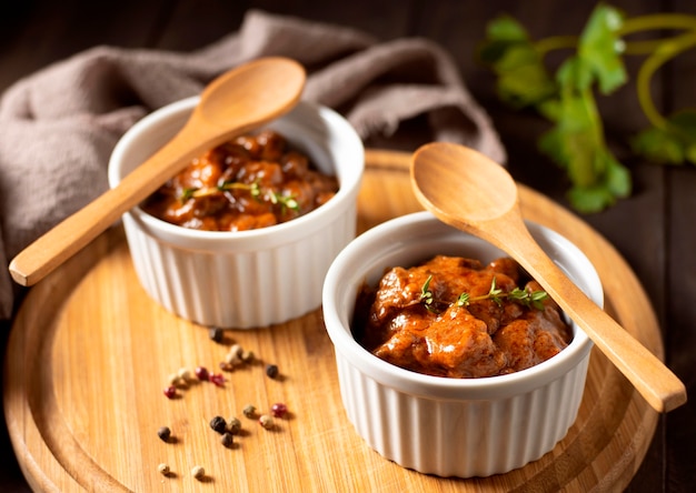 Photo winter food stew in bowl and spices on wooden board