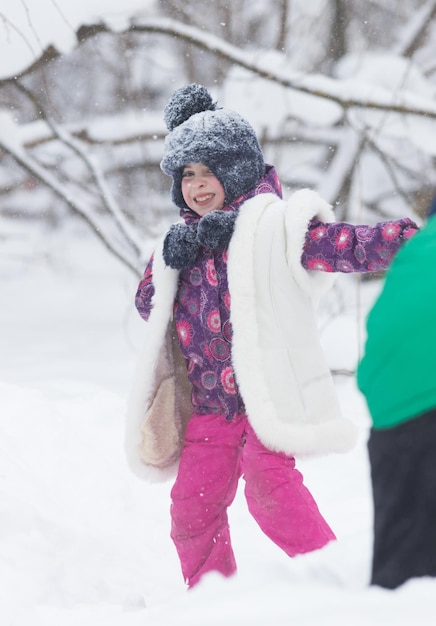 遊ぶことを楽しんでいる冬の森の幸せな少女