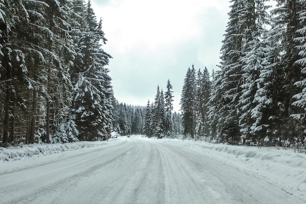 Winter forest road covered with ice and snow, distant car coming in opposite  direction. Dangerous driving conditions.