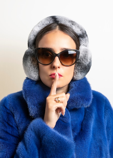 Winter fur earmuffs on woman in blue fur coat.