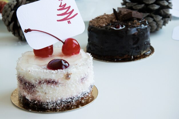 Winter gebak thema's - heerlijke taarten met wenskaart op witte achtergrond, dennenappels op achtergrond
