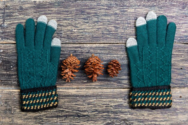 Winter gloves and pine cone on wooden background. Christmas decoration