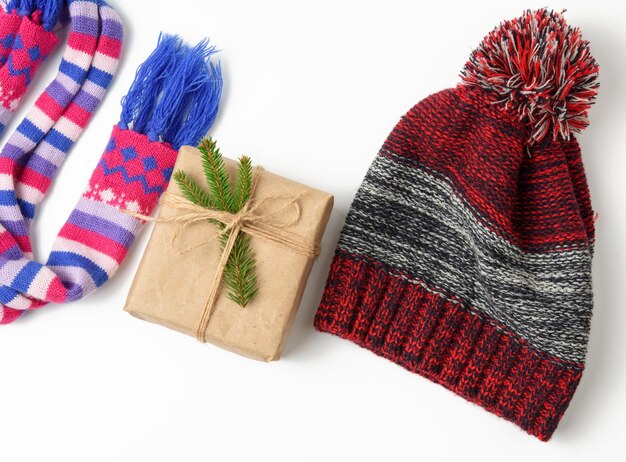 Photo winter hat gift box and multicolored knitted scarf on a white background a set on a white back