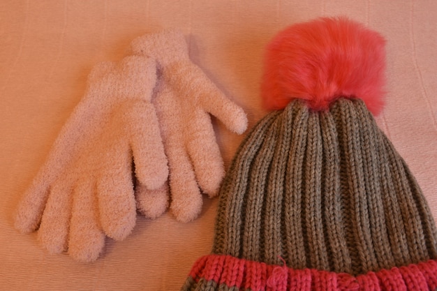 Зимняя шапка и перчатки на розовом фоне