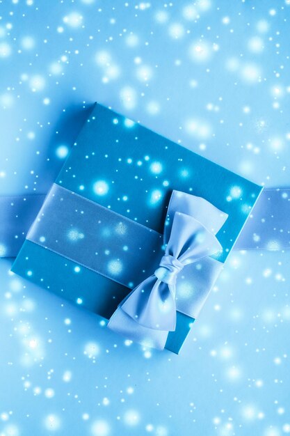 Winter holiday gifts and glowing snow on frozen blue background christmas presents surprise