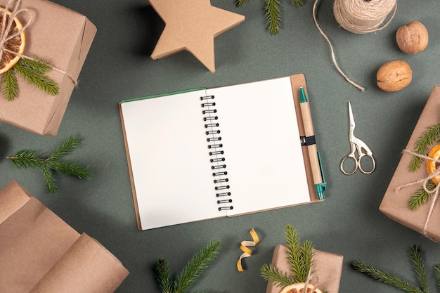 Mockup di vacanze invernali scatole di blocco note bianche vuote, spago di carta artigianale e decorazioni naturali per avvolgere i regali di natale di capodanno su sfondo verde concetto zero rifiuti buon natale mockup