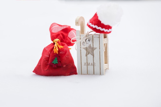 Winter holidays background:  red sack with Christmas present close to wooden made sleigh