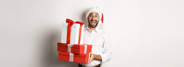 冬休みとお祝いの幸せな男は、贈り物を持ち、サンタを着てクリスマスプレゼントを持ってきます