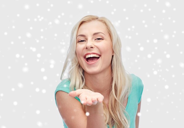 winter holidays, christmas and people concept - smiling young woman or teenage girl holding something on hand over snow