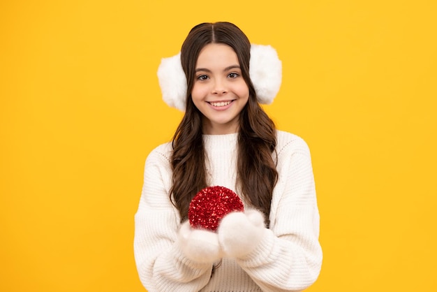 Winter holidays concept Cheerful teenage girl in xmas sweater wishing merry Christmas standing against yellow background