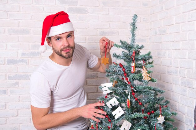 冬休みの準備とお祝い。男サンタはジンジャーブレッドスタークッキーでクリスマスツリーを飾ります。自家製デザート、装飾品、装飾品。メリークリスマスと新年あけましておめでとうございます。