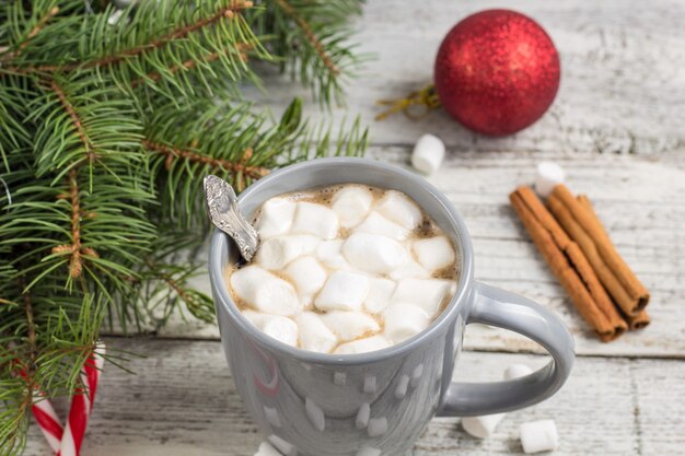 Bevanda calda invernale. cioccolata calda di natale o cacao con marshmallow sulla tavola di legno bianca con decorazioni natalizie