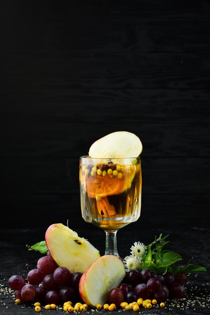 Winter hot drinks from white wine of apples sea buckthorn and\
cinnamon in the glass top view on a black background