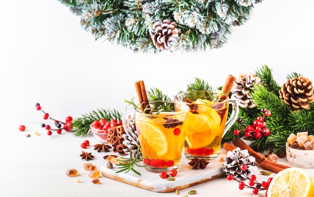 Winter hot tea with cranberry lemon and spices in glass cup in Christmas or New Year's table setting white background