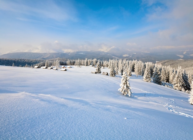 Winter kalm berglandschap met groep schuren en bergkam achter