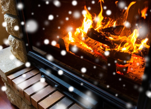 winter, kerstmis, warmte, vuur en gezelligheid concept - close-up van brandende open haard thuis met sneeuw